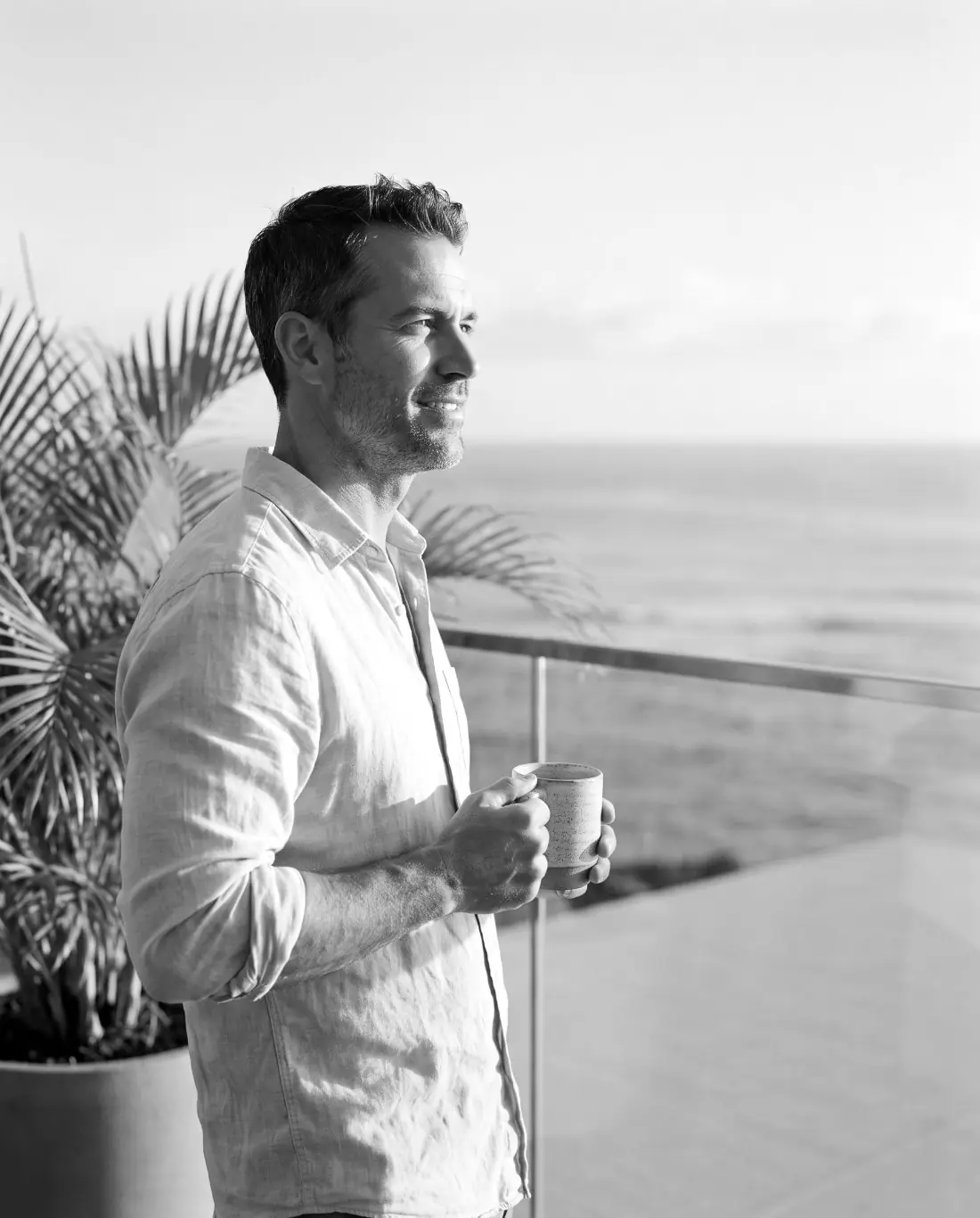 A man in his forties on his deck in the morning with a coffee
